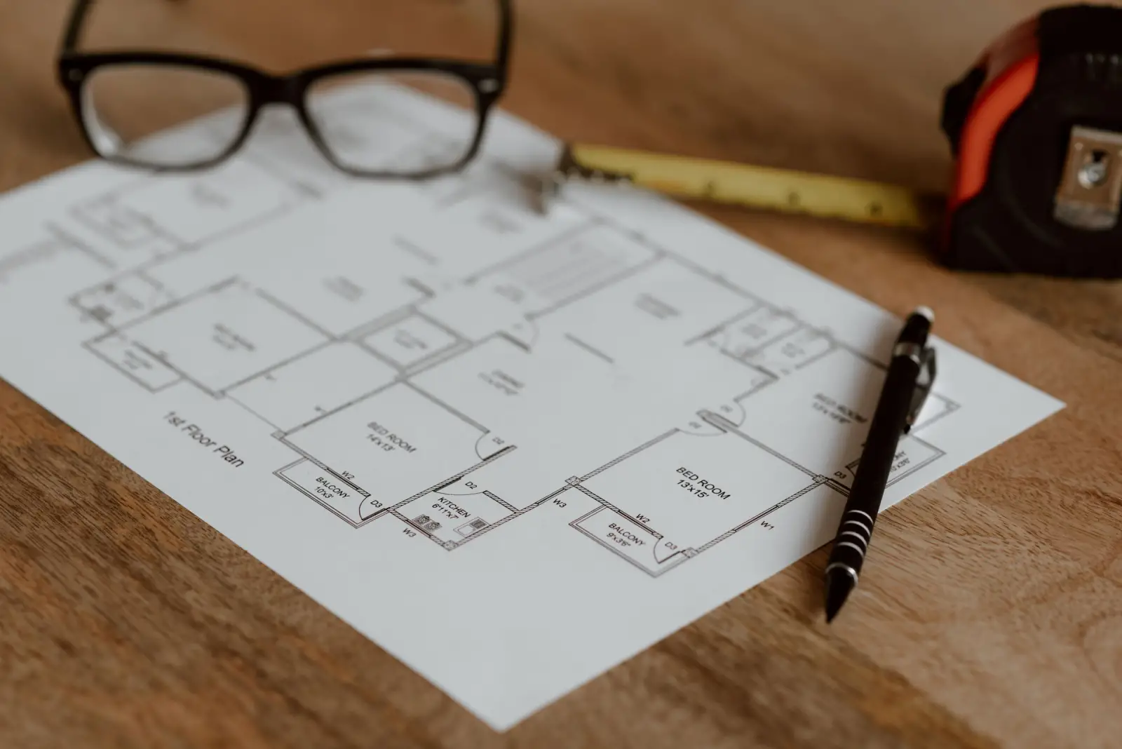 Floor plan with reading glasses, pen and measuring tape